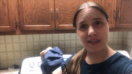 A woman holding a blue cloth in front of a washing machine.