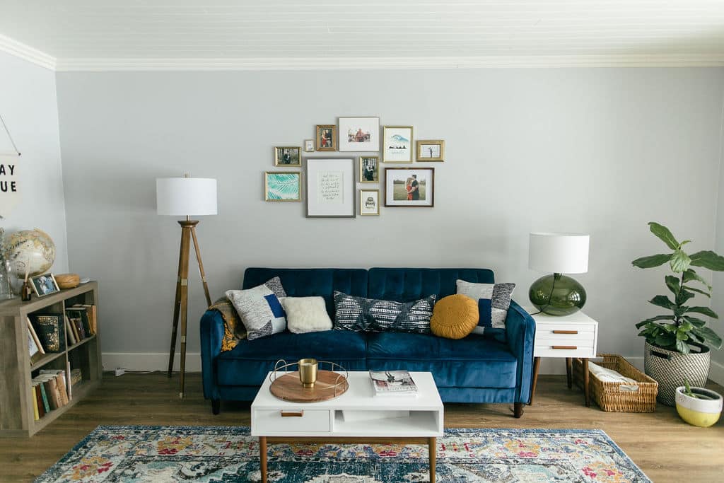 A living room with a blue couch and a rug.