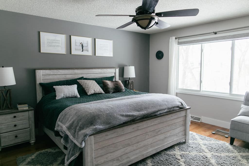A gray bedroom with a ceiling fan and a bed.