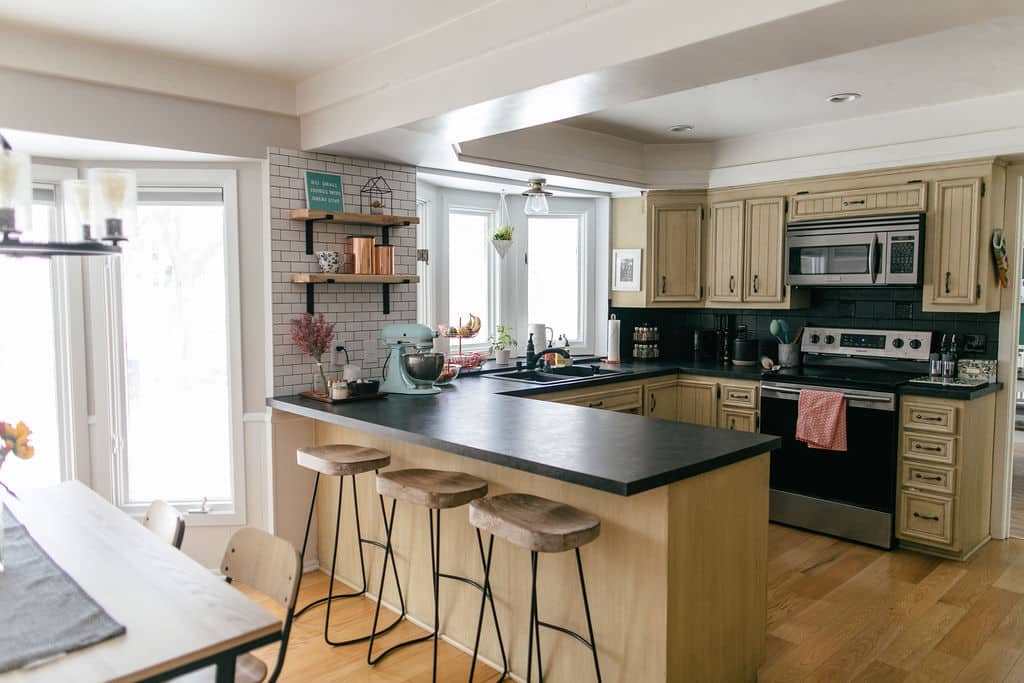 A kitchen with black counter tops and stools.