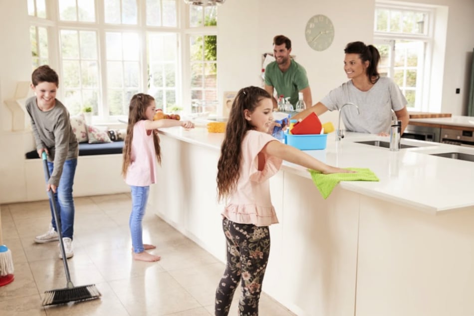 A family cleaning the kitchen with a mop.