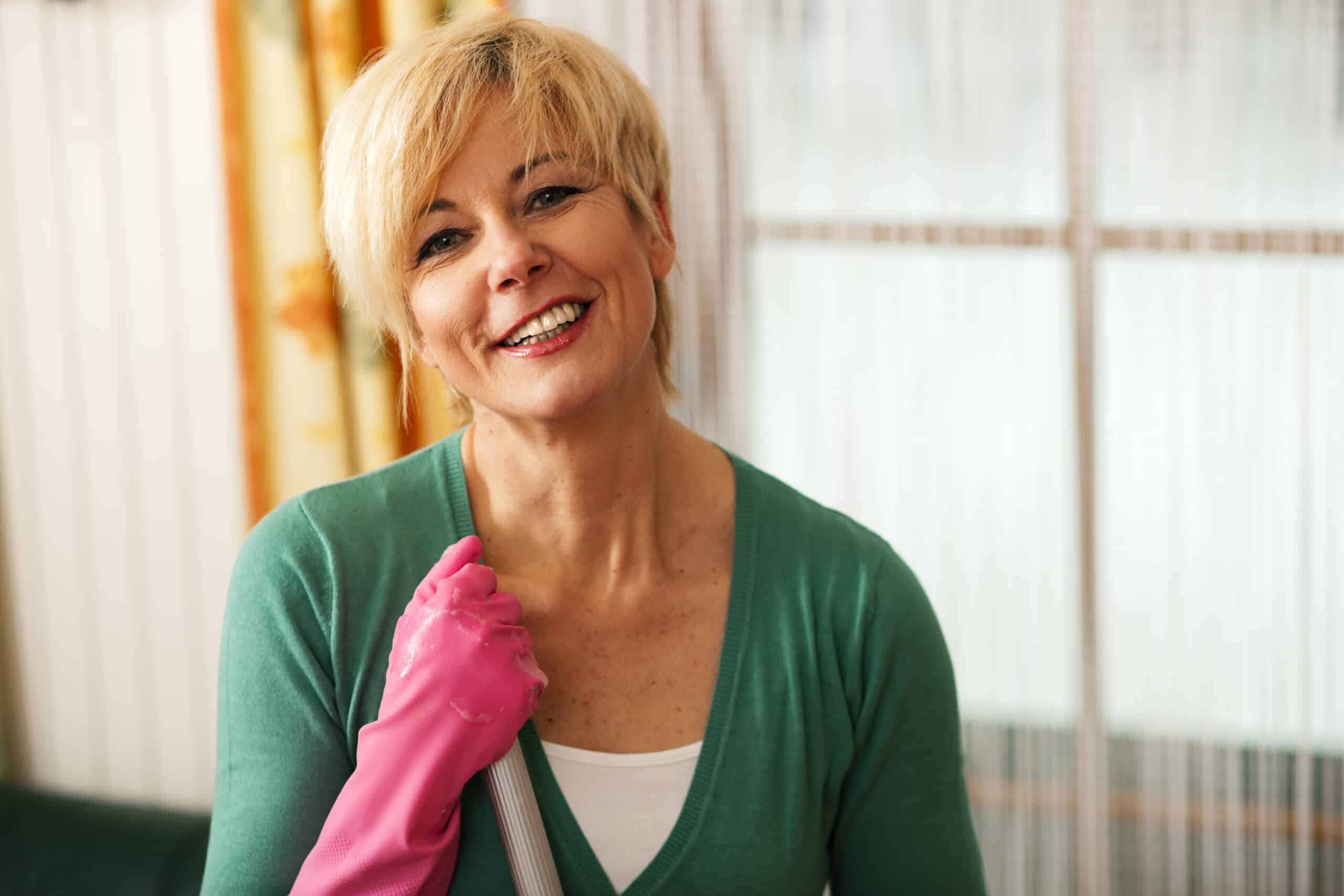 A woman wearing pink gloves and a pink mop.