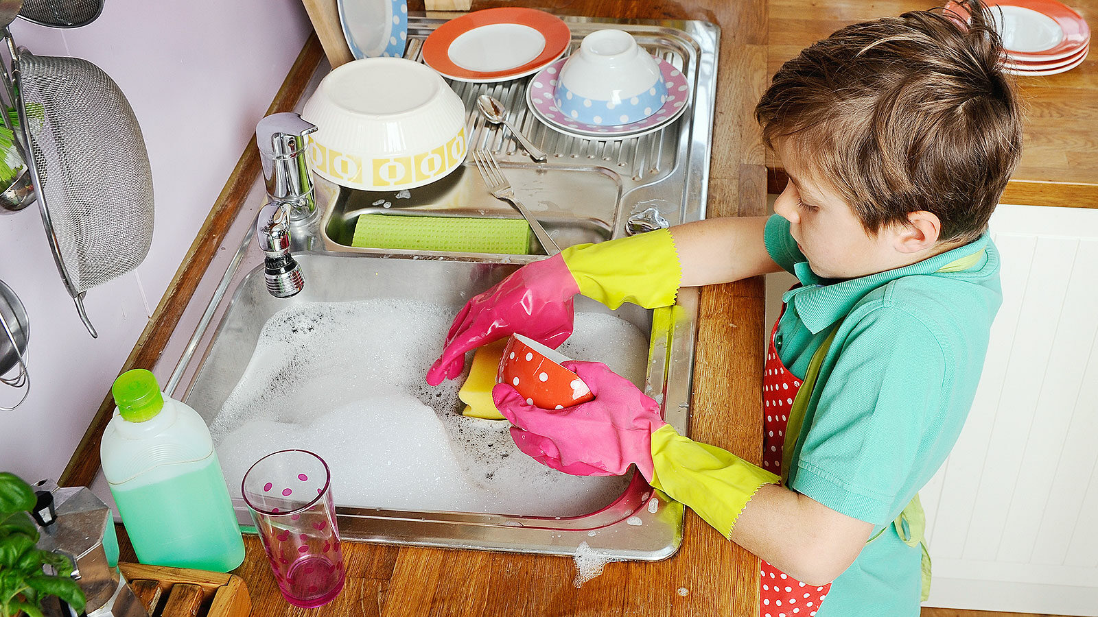 A young boy diligently completing chores in a kitchen sink.