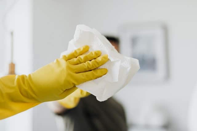 A person wearing yellow rubber gloves is holding a piece of paper.