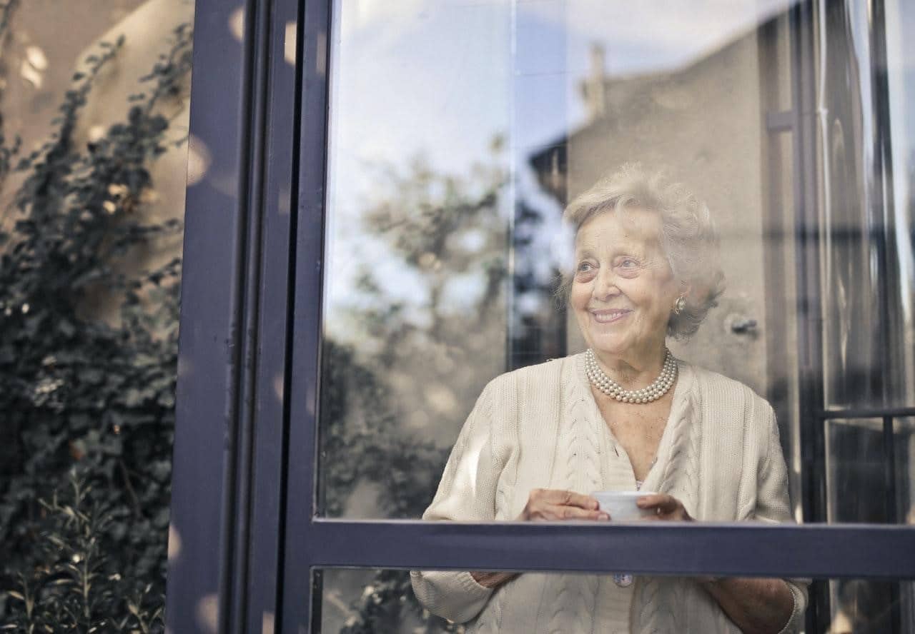 An elderly woman looking out of a window.
