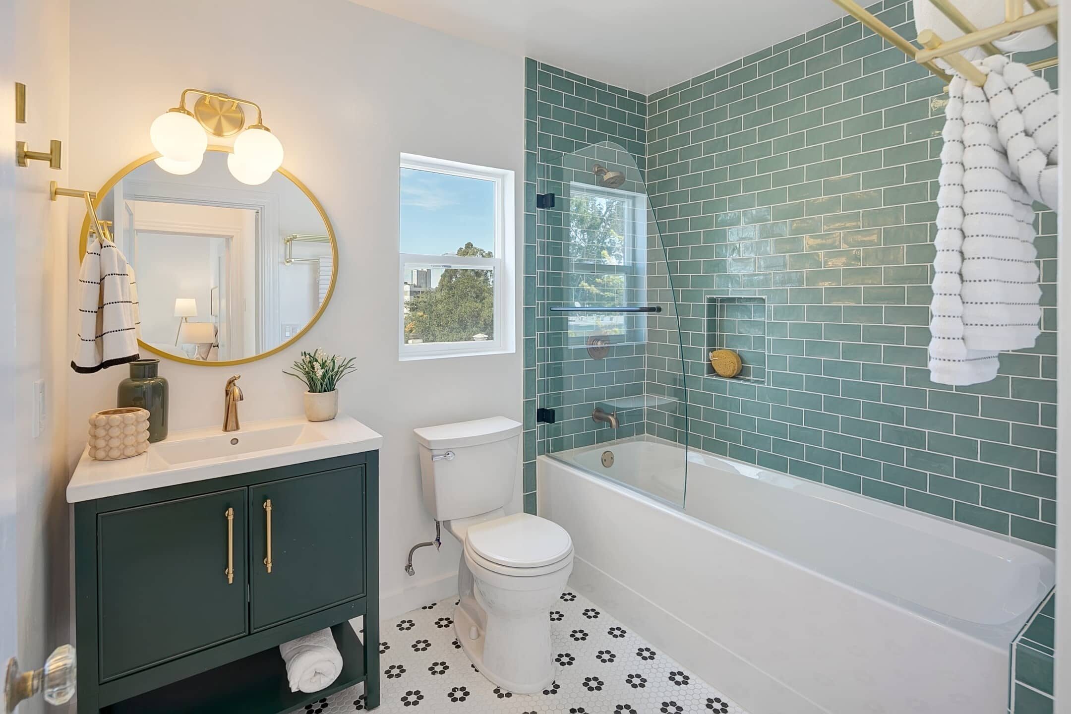 A bathroom with green tile and gold fixtures.