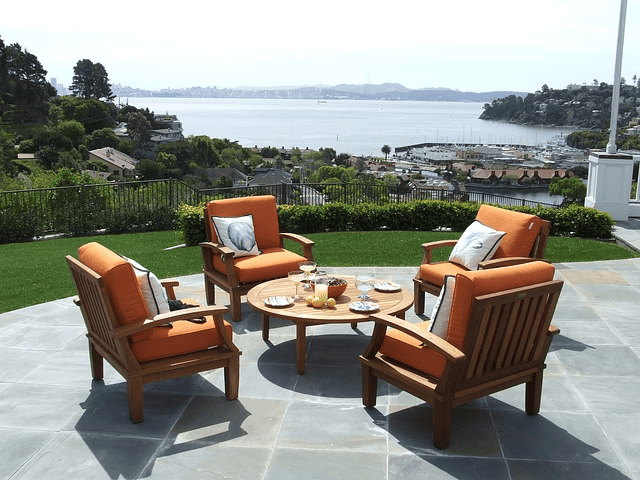 A budget-friendly patio furniture set with orange cushions and a view of the ocean.
