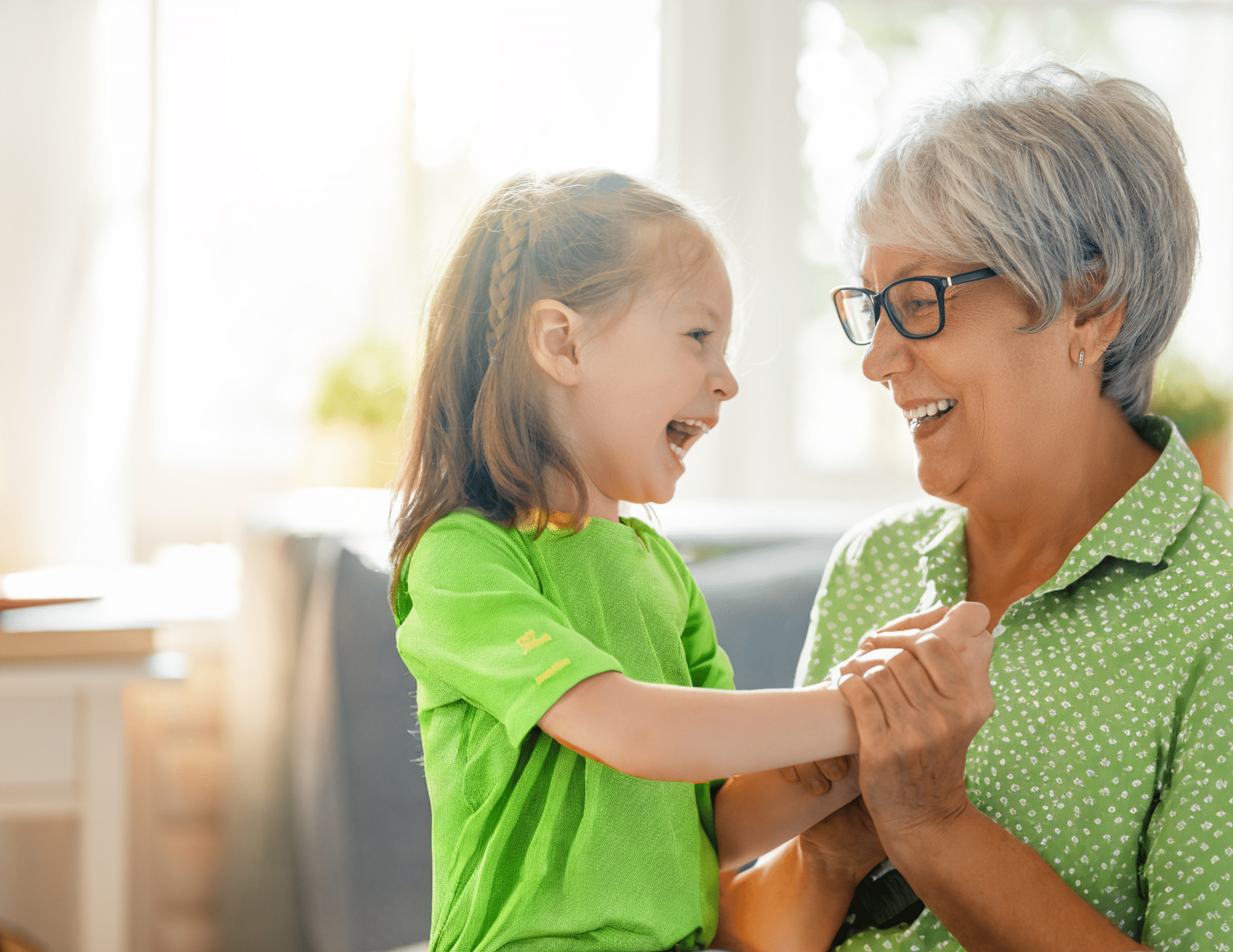 An older woman and a little girl laughing together while house cleaning.