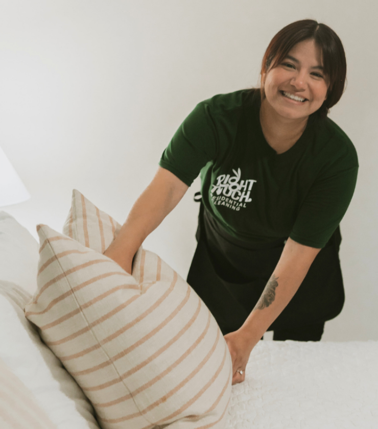 Cleaning technician making a bed with a smile on her face