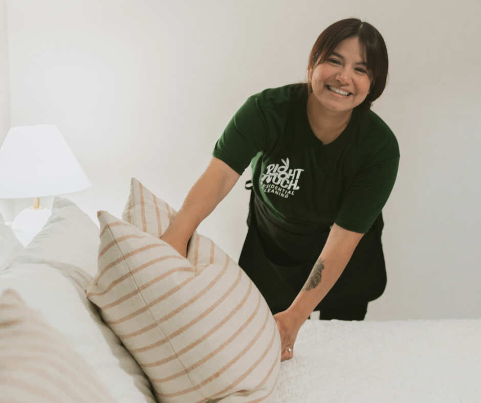 Cleaning technician making a bed with a smile on her face