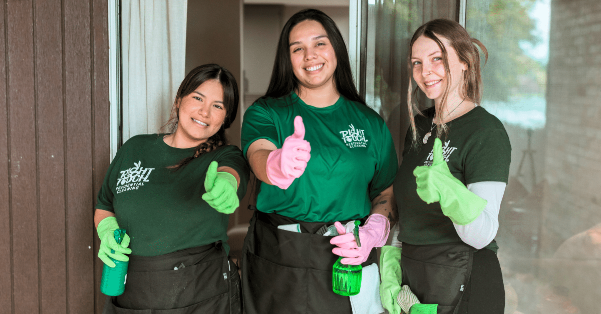Three women, dressed as house cleaners, smiling and giving thumbs up.