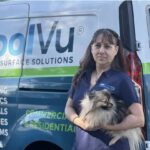 Woman business owner looking proud, holding her dog, in front of a CoolVu business van