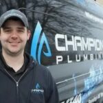 Smiling owner of Champion Plumbing standing in front of his business truck.