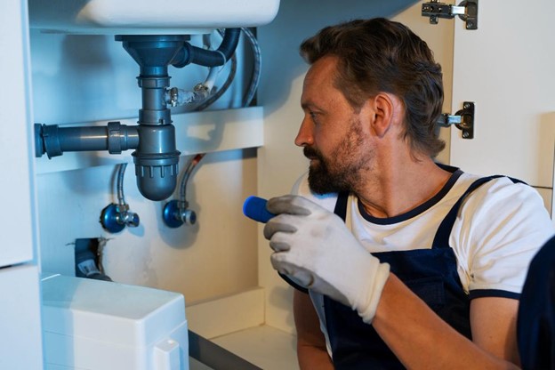 Plumber looking under a sink with a flashlight